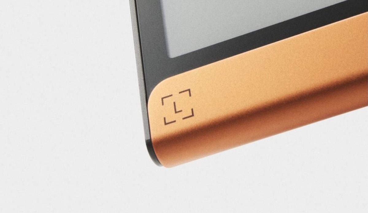 Detalle de la esquina inferior de una billetera de hardware Ledger, con pantalla gris y franja color cobre con el logo de la marca