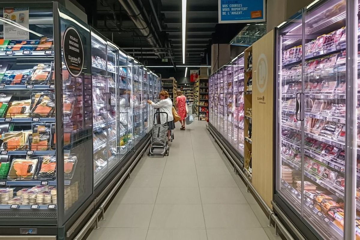 Pasillo de un supermercado E.Leclerc en Francia, con refrigeradores exhibidores de carnes y fiambres a ambos lados y dos clientas al fondo