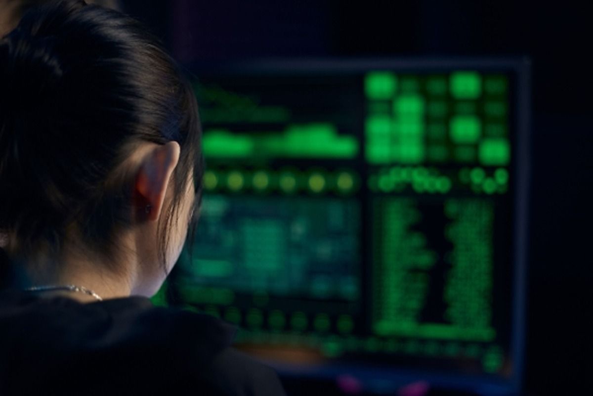 Una persona de espaldas frente a una pantalla con datos en verde