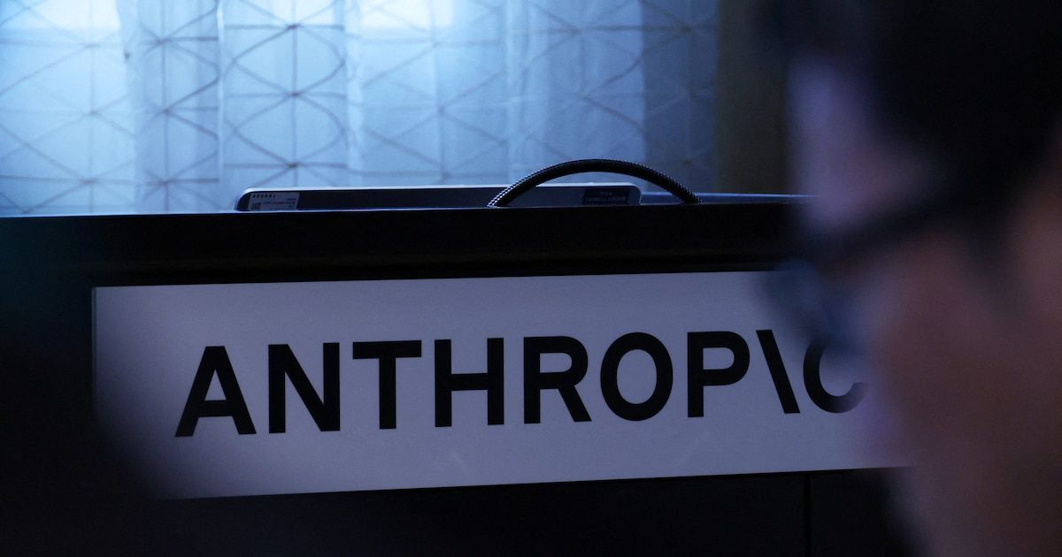 Cartel con el logotipo de Anthropic sobre un atril, con una persona desenfocada en primer plano