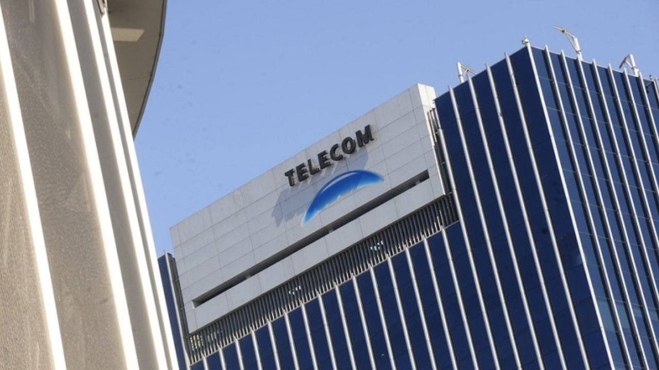 Fachada de la sede de Telecom en Buenos Aires, con el logo de la empresa sobre un edificio de vidrio azul y un cielo despejado