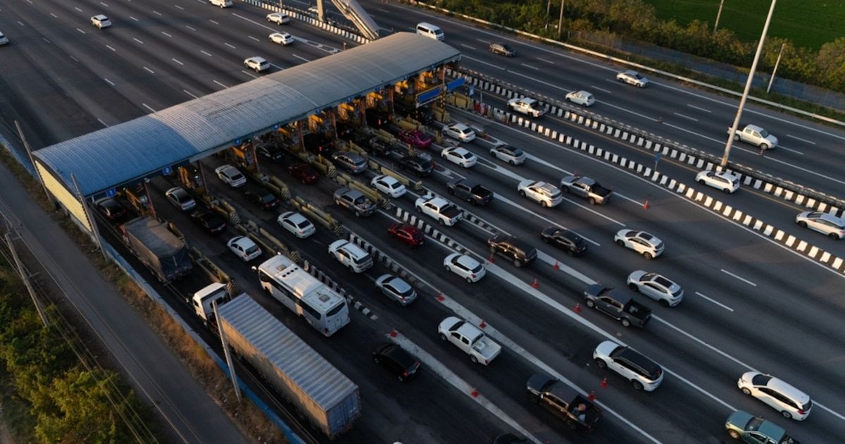 Vista aérea de un peaje de autopista con varios carriles y decenas de autos y camiones esperando para pasar