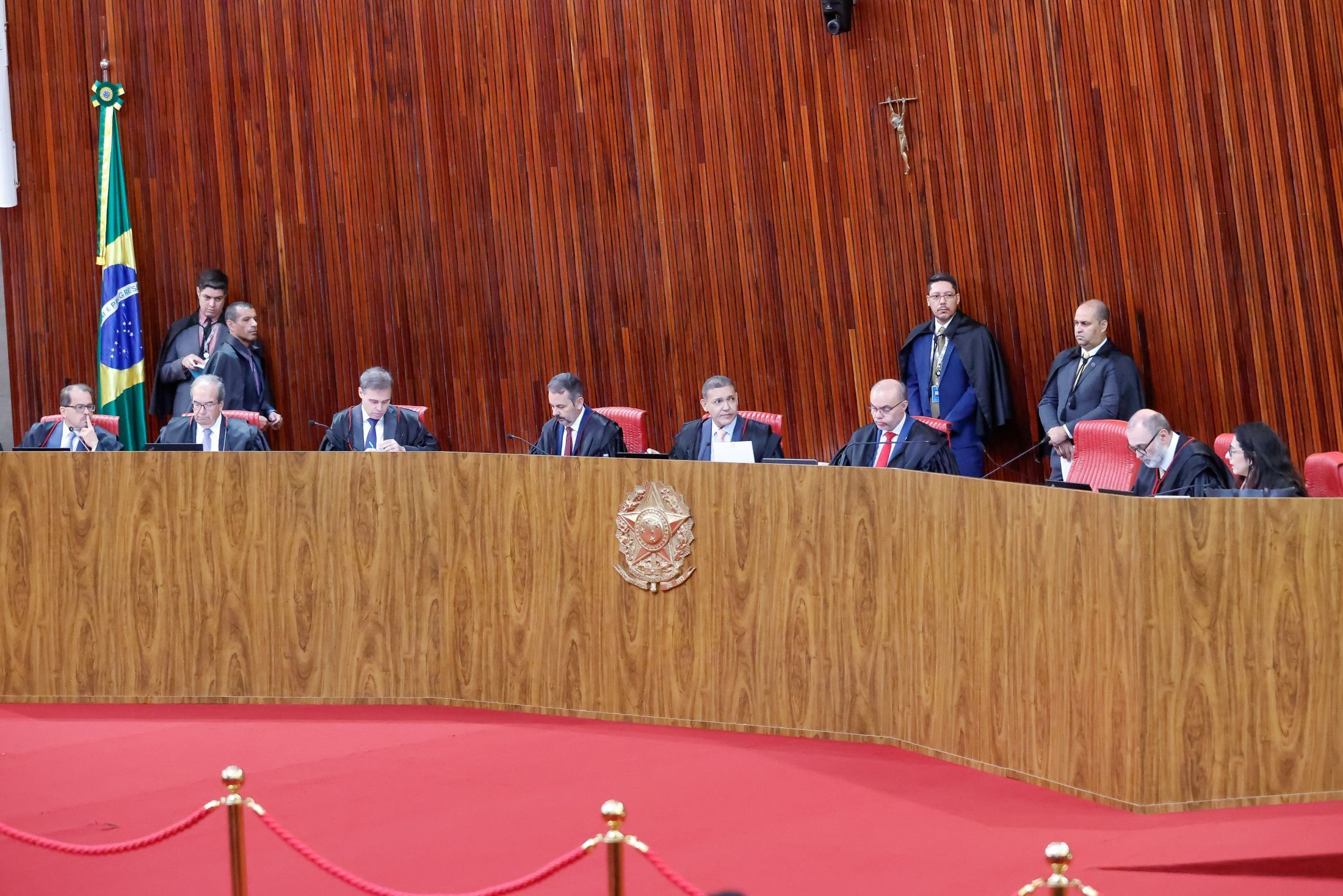Ministros del Tribunal Superior Electoral de Brasil sentados en el estrado del plenario, junto a la bandera brasileña
