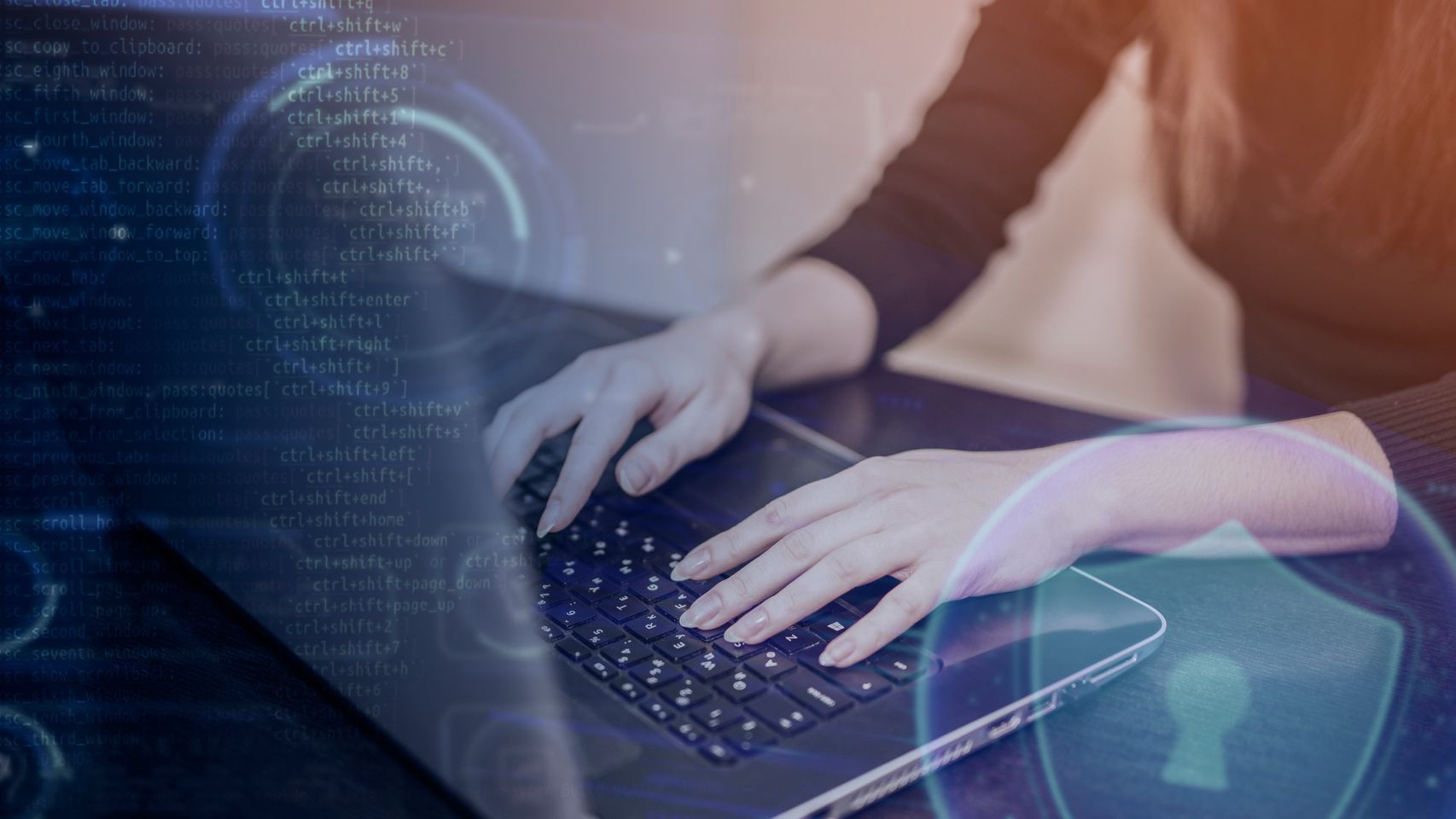 Manos sobre el teclado de una computadora portátil con un escudo con candado y líneas de código superpuestas
