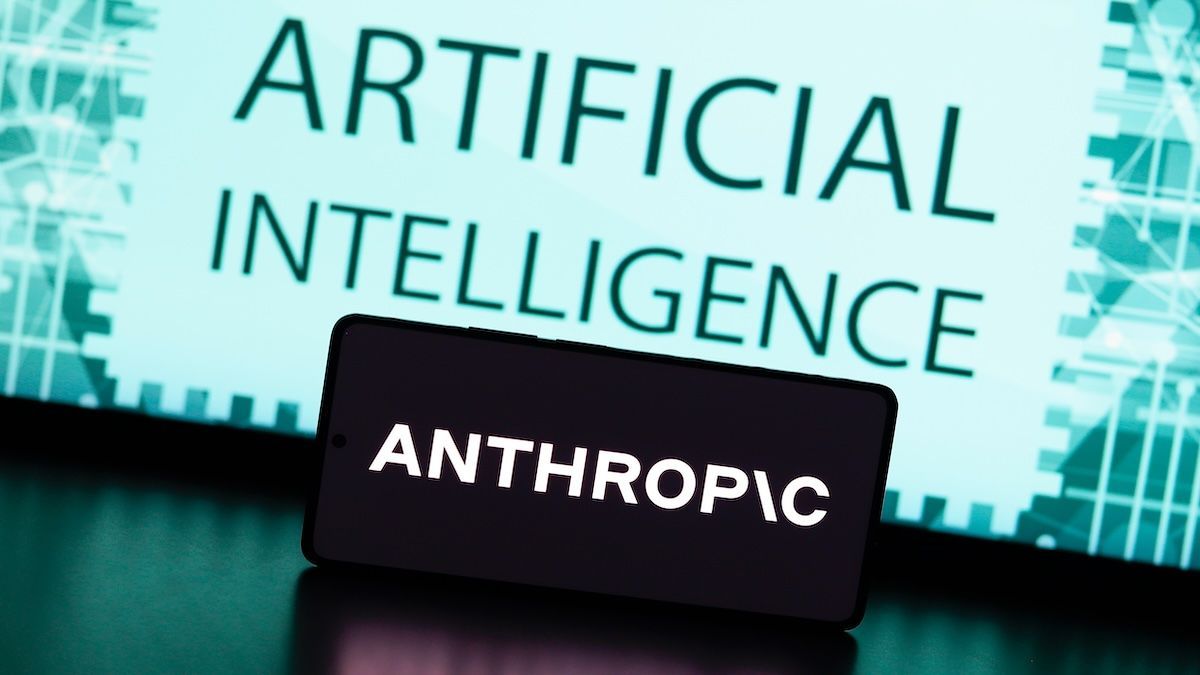 Celular con el logo de Anthropic apoyado frente a una pantalla con la leyenda Artificial Intelligence