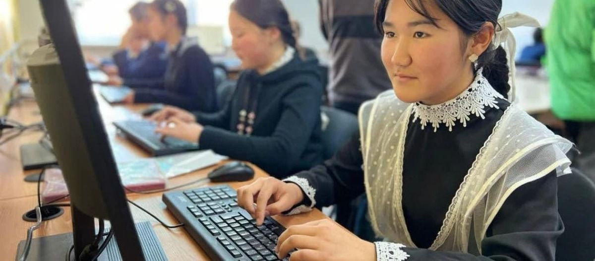 Estudiantes trabajan en computadoras de escritorio en un aula de informática