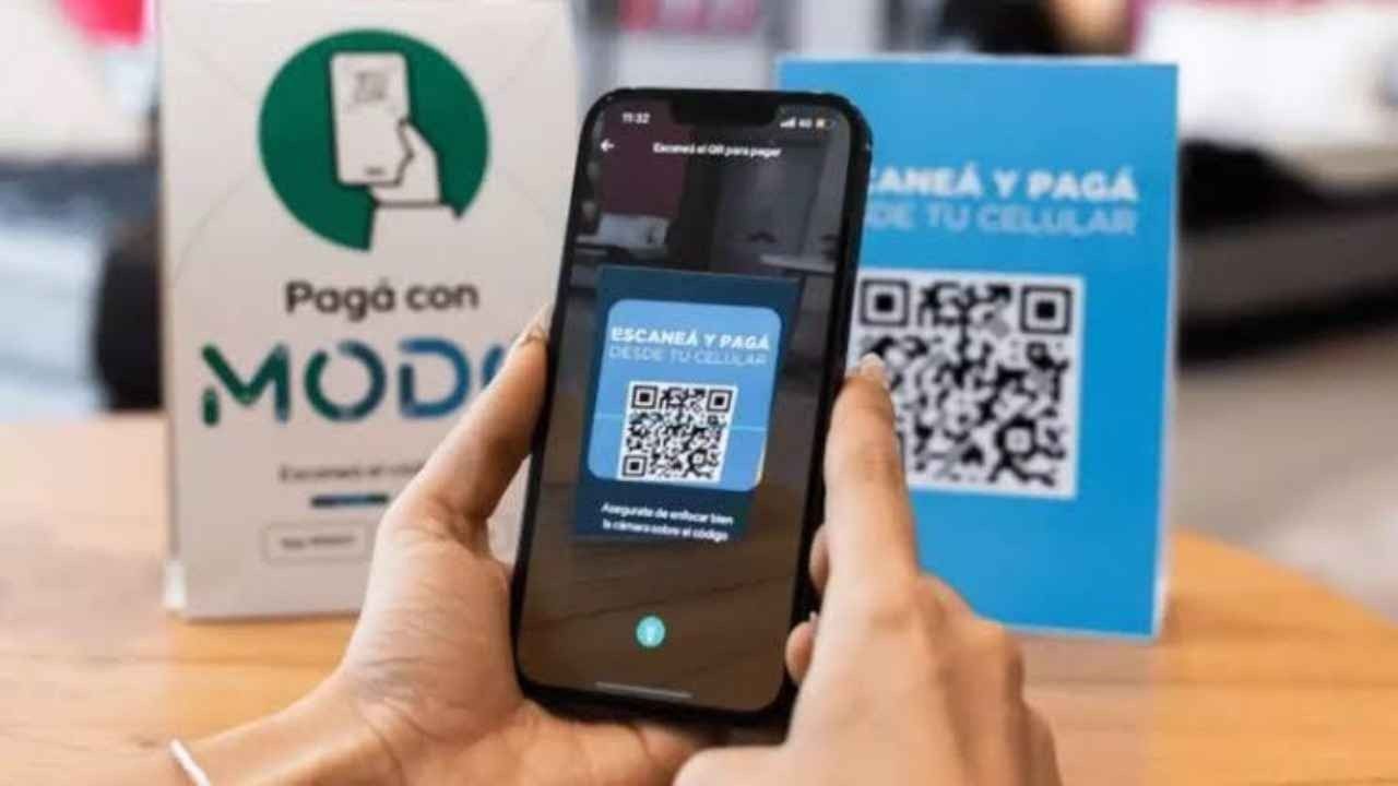 Una persona escanea con el celular un código QR para pagar en el mostrador de un comercio