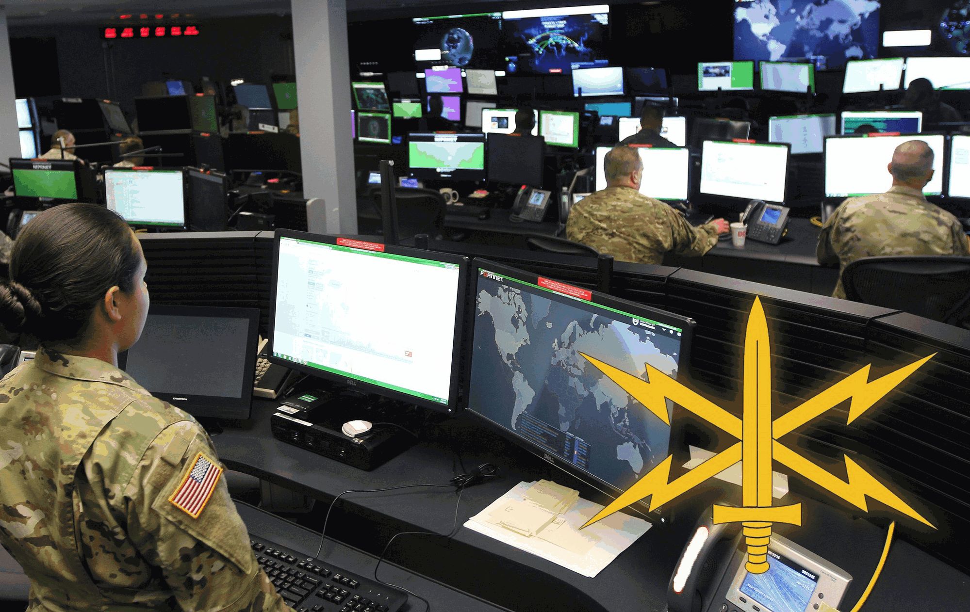 Soldados del Ejército de Estados Unidos frente a pantallas en un centro de operaciones cibernéticas, con el emblema dorado de la rama cibernética del Ejército