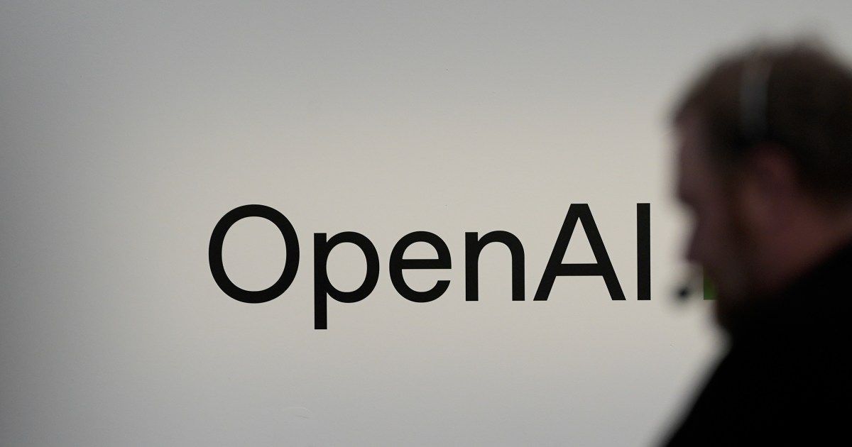 Logo de OpenAI en una pared blanca, con la silueta desenfocada de una persona en primer plano