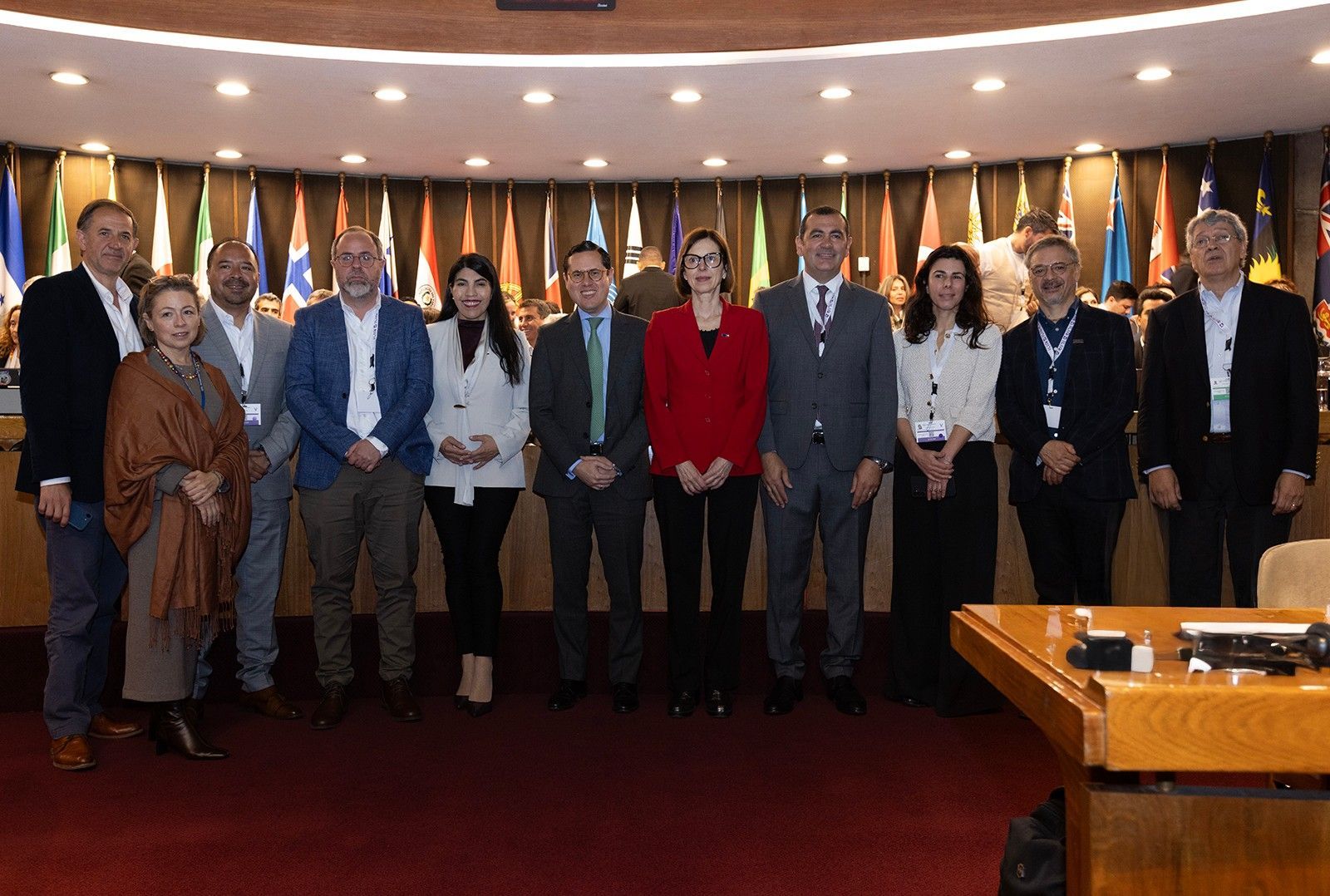 Autoridades e investigadores posan en la sala de conferencias de la CEPAL, con las banderas de los países de la región al fondo, en la presentación del ILIA 2026