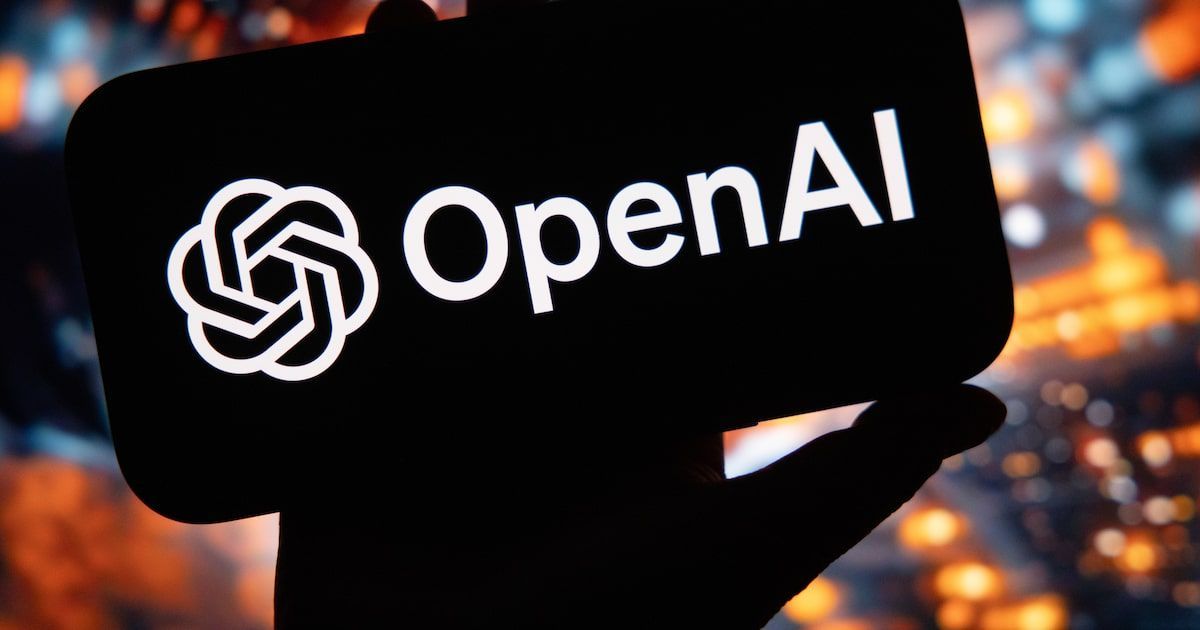 Una mano sostiene un celular negro en posición horizontal, con el logo blanco de OpenAI en la pantalla: el símbolo de espiral de nudos y la palabra OpenAI. De fondo, luces naranjas y celestes desenfocadas.