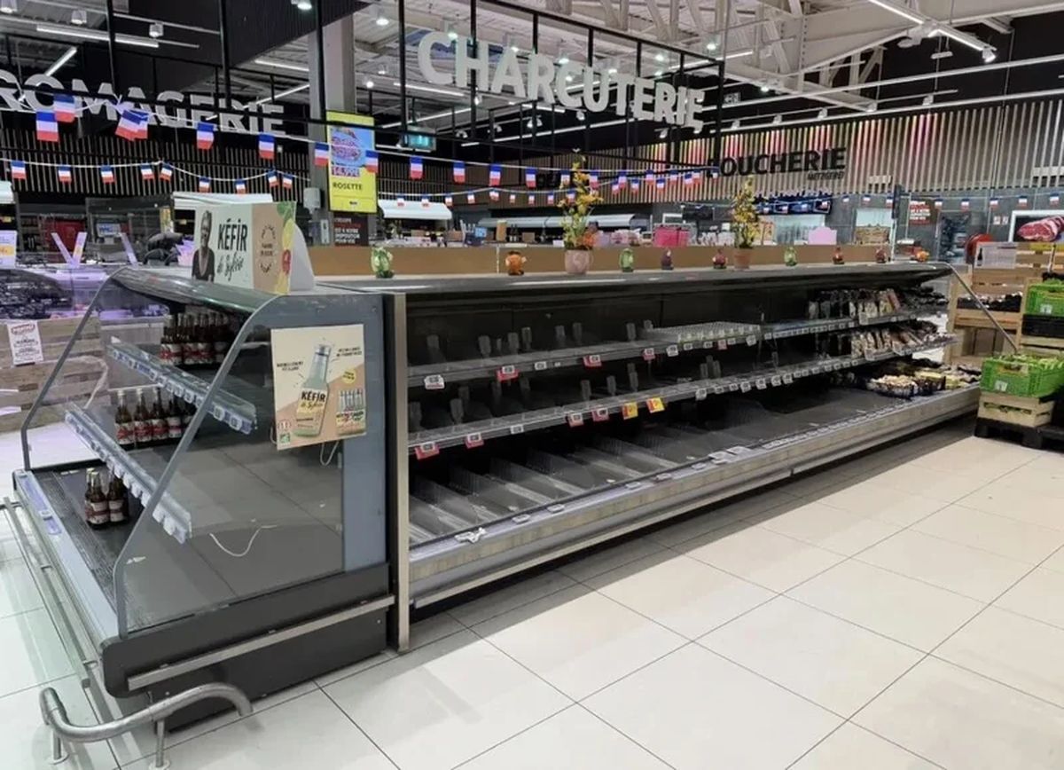 Vitrinas refrigeradas de charcutería vacías en un supermercado de Francia, con los estantes sin productos y los carteles de precios a la vista